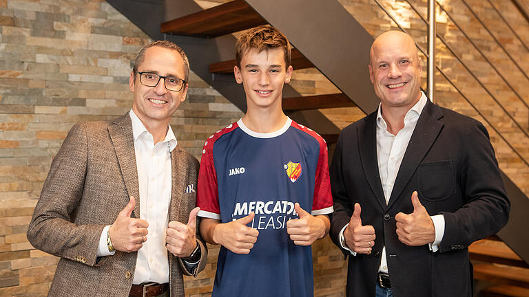 Matthias Schneider (links) und Dr. Norman Hoppen mit einem Spieler der JFG Werntal Kicker.